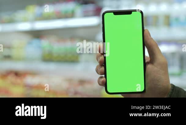 Close up view of hand holding modern mobilephone with empty green ...