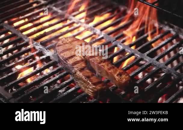 Juicy salmon steak with strips is grilled on a barbecue in a flame of