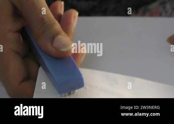 A women is stapling the papers with stapler and fastening those with ...