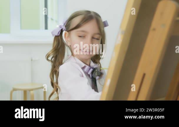 little girl paints a picture and looks at the camera. Happy little girl ...