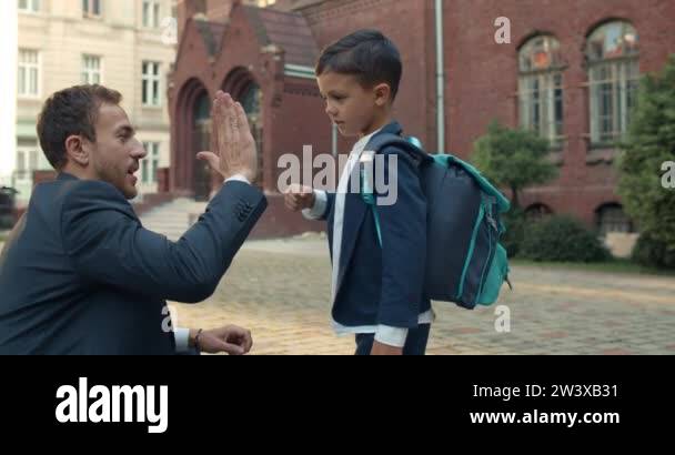 Young father in suit and teen boy doing goodbye ritual before going to ...
