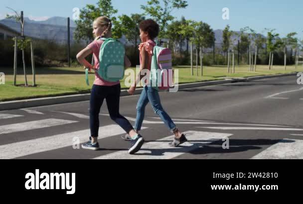 Caucasian and African American girls crossing the road on a pedestrian ...