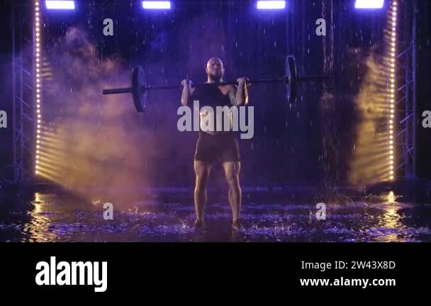 Strength Dripping Weightlifter lifts the bar above his head. Strength training with a ...