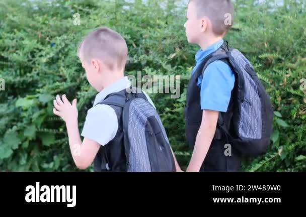 two boys, schoolchildren in black school uniforms with backpacks go to ...