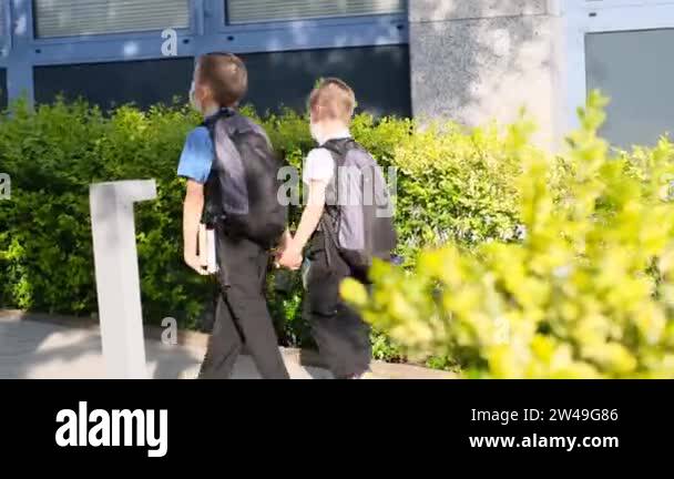 two boys, schoolchildren in black school uniforms with backpacks go to ...