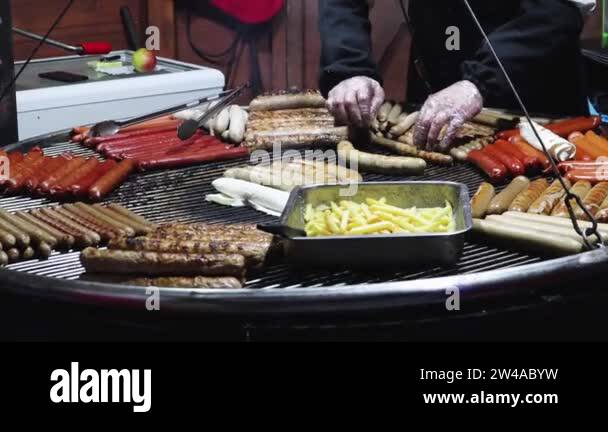 Grilled sausages and fries on a large metal rack at the festive evening ...