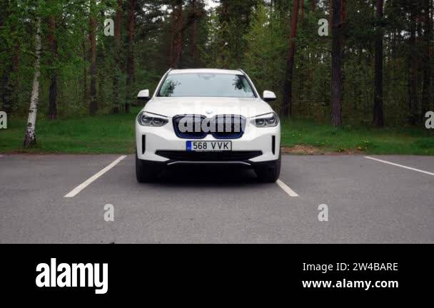 BMW iX3 fully electric car pulling out of a parking space and driving ...