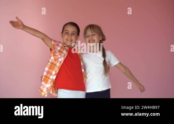 little smiling girls, sisters, best friends hug on a pink background ...