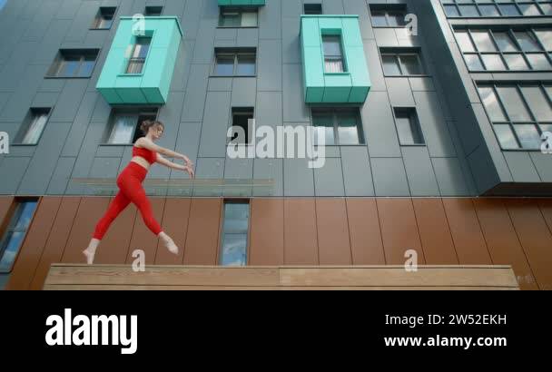 Gymnastic woman in red does acrobatic exercices on the bench in the ...