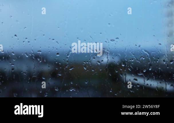 Rain water drops falling down on the window blue glass. drops on glass ...