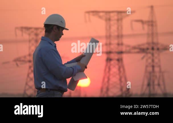 Electrician and high voltage electric lines at sunset. power engineer