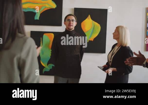 Female gallery manager introducing young male artist to visitors ...