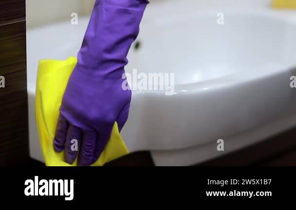 Male hands in rubber gloves wiping a sink and water tap. Man with rag ...
