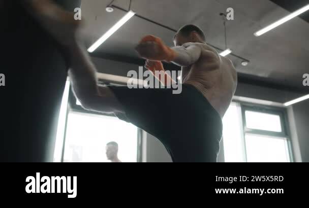 Kickboxer does middle kick to the boxer bag in slow motion, fighter is ...