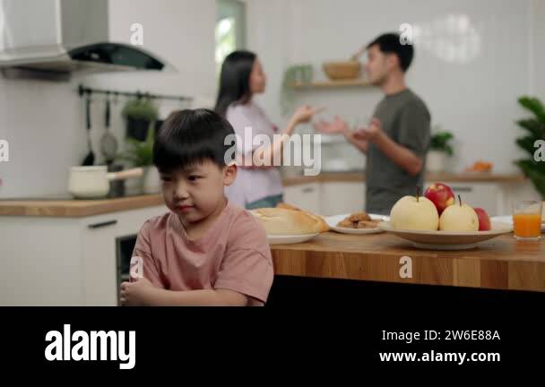 Asian boy kid sitting and use hands close ears because parents having ...