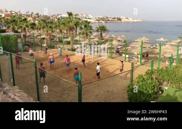 People tourists with sunburns back plays volleyball on the beach of red