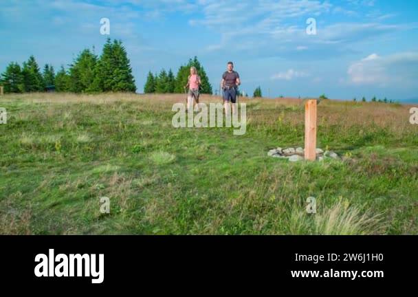 Two hikers arriving to the top of a hill and positioning on the healing ...