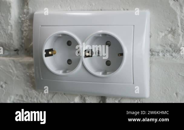 Inserting an Electrical Power Cord into a Socket on the Office Wall ...