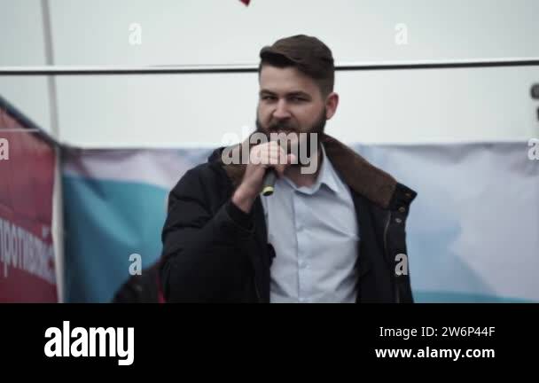 Angry male speaker with microphone on stage delivers important message ...