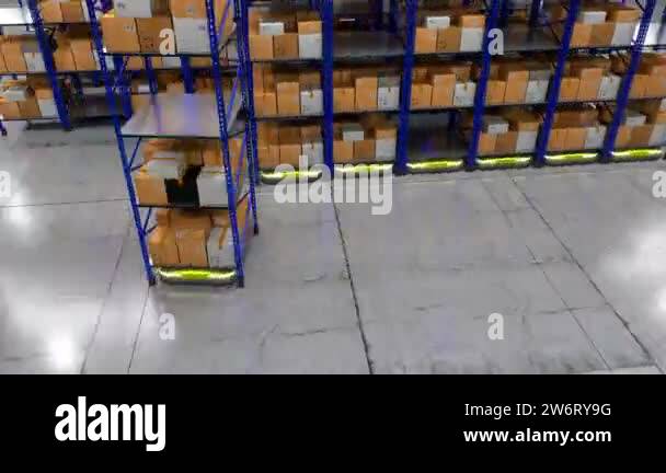 Autonomous robots moving around rack shelves with packages in warehouse ...