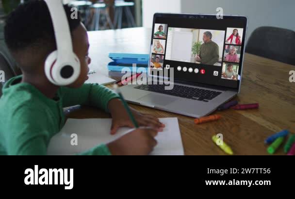 Schoolboy using laptop for online lesson at home, with diverse teacher ...