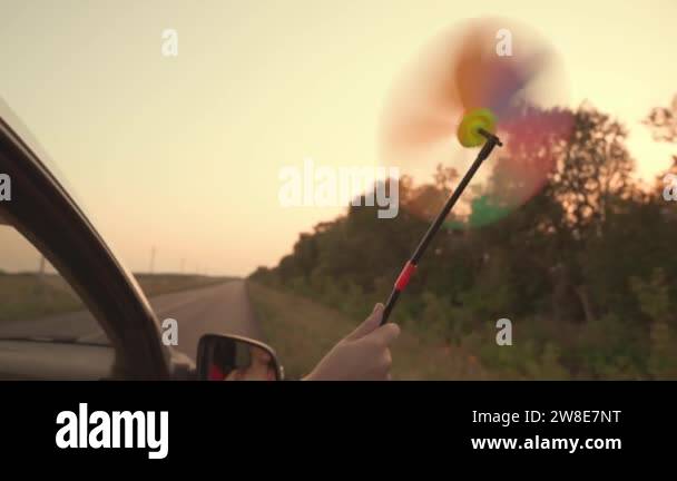 free girl waving a pinwheel out of the car window in wind, travel ...