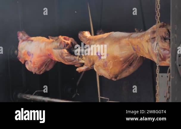 Process of cooking two ram carcasses on spit at street food market ...