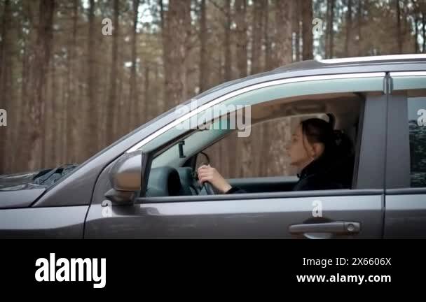 Woman practicing driving car, cruising along deserted forest trail with ...