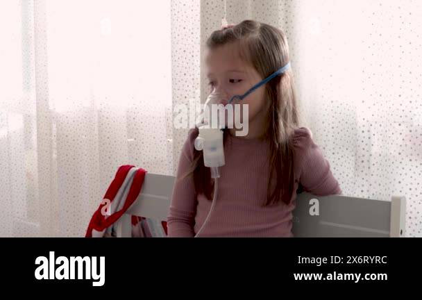 Cute little girl in the mask of an inhaler. Procedure of inhalation at ...