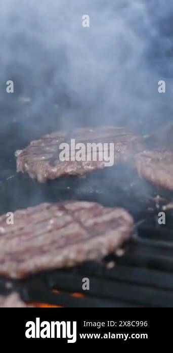 Tasty meat for a burger cooked on a fiery barbecue grill. Close up of ...