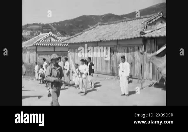 1950 - Marines walk through a Korean village where a local woman cleans ...