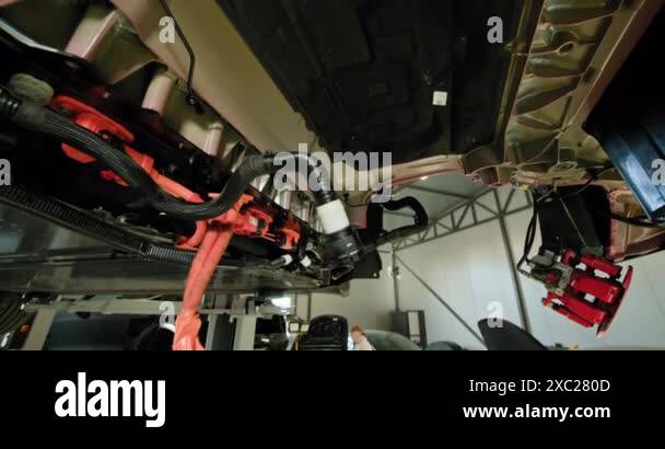 Mechanic inspecting the underside of an electric vehicle, focusing on