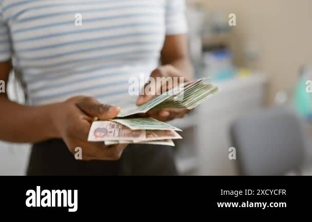African woman with braids counting dirhams in an office setting implies ...