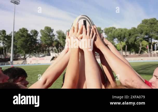 Group of female rugby players raising a rugby ball together ...
