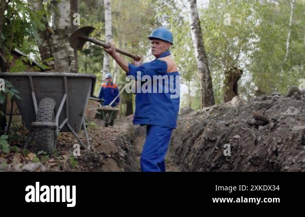 An industrious construction worker in a blue uniform and safety gear is ...