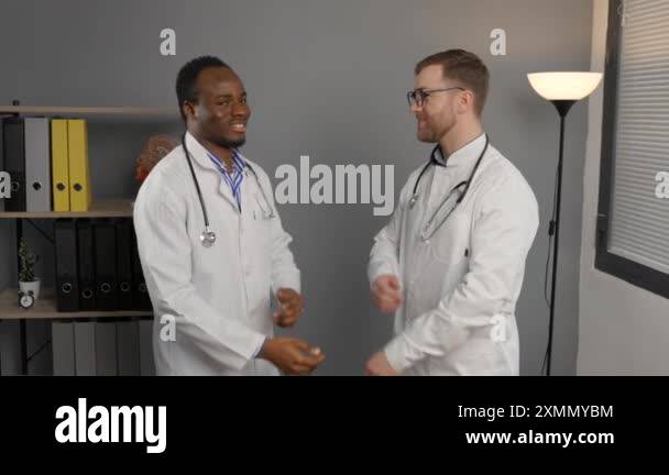 Two men in white lab coats standing together near desk Stock Video ...