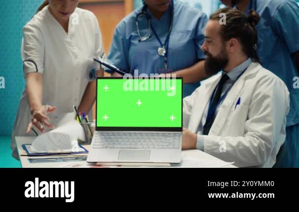 Team of doctors consulting analytics next to green screen on laptop in ...