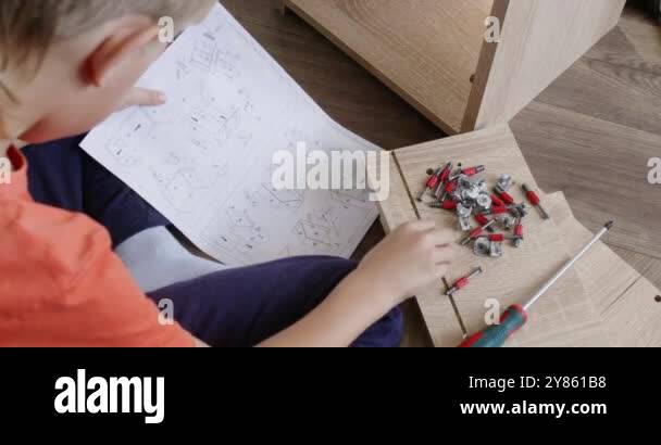 Young boy reading assembly instructions while putting together ...