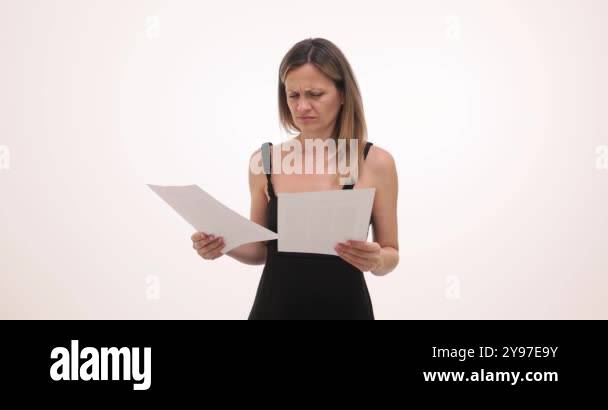 Young woman with puzzled expression examines documents on white ...