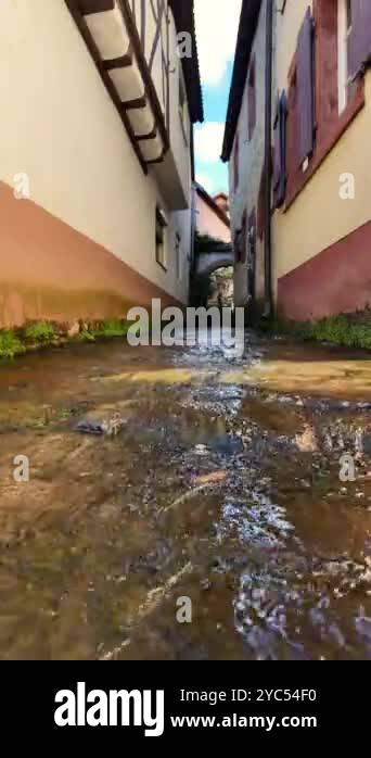 A serene stream meanders gently through a narrow alley in a charming ...