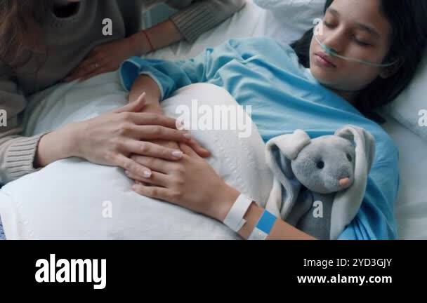 Top view of mother stroking hands of little sick daughter sleeping or ...