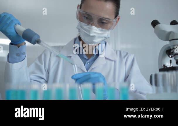 Scientist woman wearing a lab coat, mask, and safety glasses is using a ...
