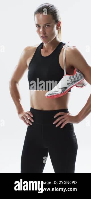 Vertical video: Caucasian female athlete holding running shoe, white ...