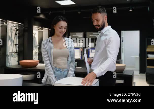 A sales consultant shows a customer a modern sink design in a plumbing ...