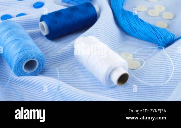 Close-up view of thin tufts blue cotton jersey, buttons and spools of ...