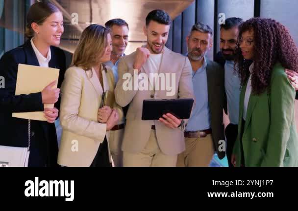 A diverse group of business professionals in formal attire celebrate a ...