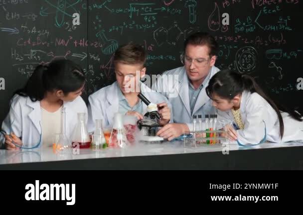 Multicultural student looking under microscope while cute girl inspect ...