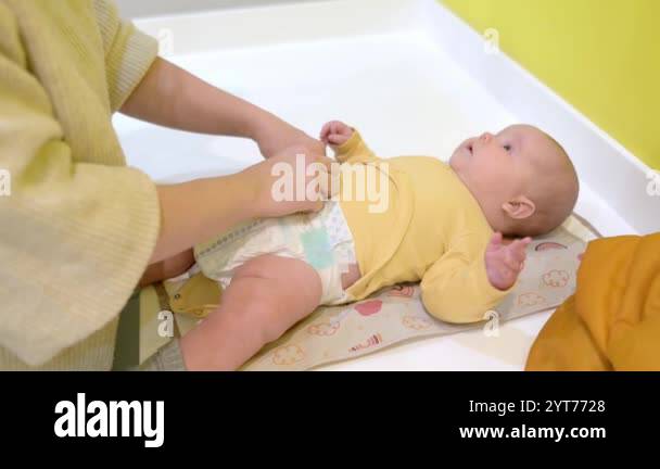 Mom changes the diaper for her newborn baby. Cute two-month-old boy or ...