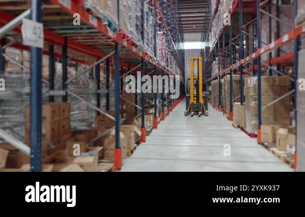 Forklift is moving through a warehouse aisle filled with shelves full ...