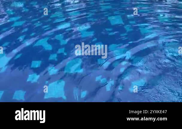 Clear blue water surface with gentle ripples and light reflections ...